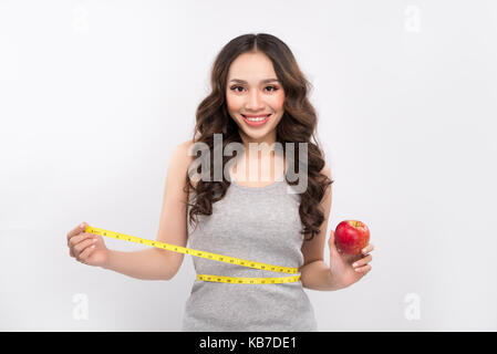 Woman measuring her waistline and holding apple. Weight losing concept. Stock Photo