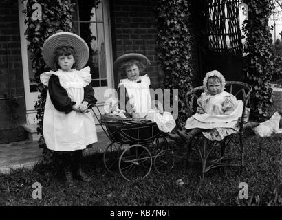 AJAXNETPHOTO.1890 - 1914 (APPROX). LOCATION UNKNOWN. - THREE LITTLE GIRLS POSING FOR THE CAMERA IN A CARDEN WITH DOLLS IN A TOY PRAM AND A DOG. PHOTOGRAPHER:UNKNOWN © DIGITAL IMAGE COPYRIGHT AJAX VINTAGE PICTURE LIBRARY SOURCE: AJAX VINTAGE PICTURE LIBRARY COLLECTION REF:AVL 172109 3 Stock Photo