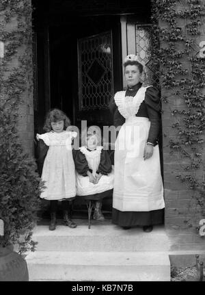 AJAXNETPHOTO. 1890 - 1914 (APPROX). LOCATION UNKNOWN. - HOUSEMAID AND TWO CHILDREN POSING FOR CAMERA ON THE DOORSTEP OF A HOUSE; ONE CHILD IS SEATED. PHOTOGRAPHER:UNKNOWN © DIGITAL IMAGE COPYRIGHT AJAX VINTAGE PICTURE LIBRARY SOURCE: AJAX VINTAGE PICTURE LIBRARY COLLECTION REF:AVL 172109 6 Stock Photo