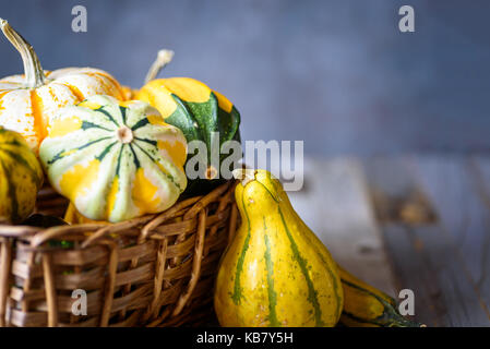 Closeup of decorative gourds and pumpkins in a basket on natural rustic wooden background Stock Photo
