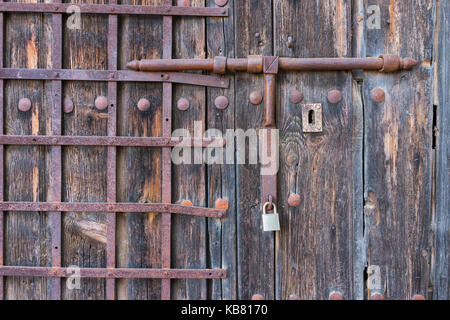 old wooden door with  wrought iron bars. Old latch wrought iron. Stock Photo