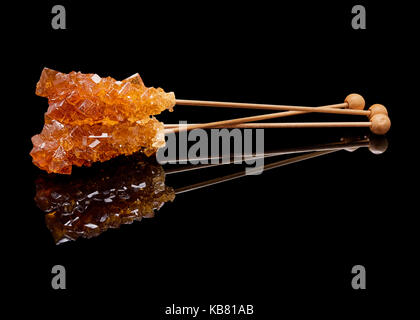 Three lying sticks of brown sugar with a real reflection on a black glossy background Stock Photo