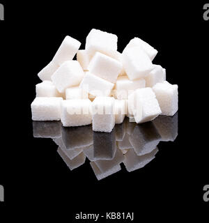 Cubes of white sugar from sugar beet with a real reflection on a black glossy background Stock Photo