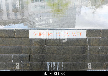 Sign on a water feature in Old Market Square, Nottingham saying slippery when wet Stock Photo
