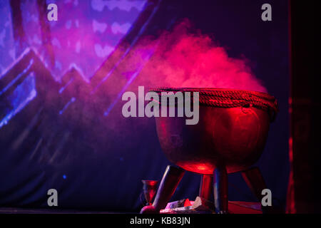 stage prop, decoration, illuminating concept. at the corner of the stage there is a smoking cast iron cauldron with legs in form of paws, nearby there Stock Photo
