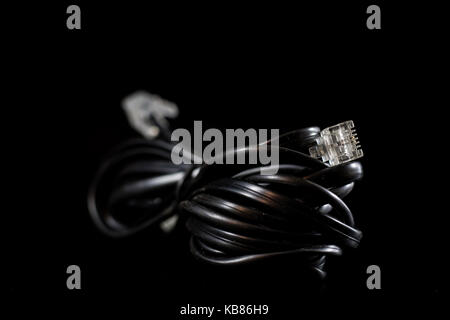 Old entangled cables, electronics and old cable connectors on a black table. Black background Stock Photo