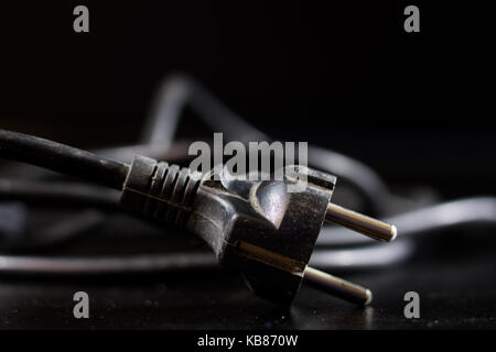 Old entangled cables, electronics and old cable connectors on a black table. Black background Stock Photo