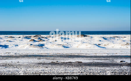 Frozen ice and sand dunes on beach in winter by empty lake horizon under clear blue sky, near Georgian Bay, Ontario, Canada. Stock Photo