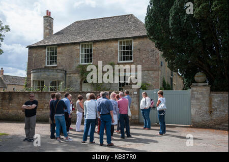 Tourists on a walking tour in Bampton, Oxfordshire, a location for scenes in the TV programme Downton Abbey, outside Churchgate House Stock Photo