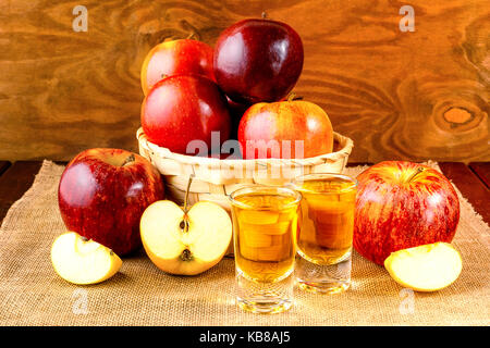 Two schnapps drinks and red apples in the wicker basket Stock Photo