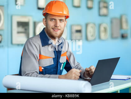 Portrait of young happy engineer working at laptop in control room Stock Photo