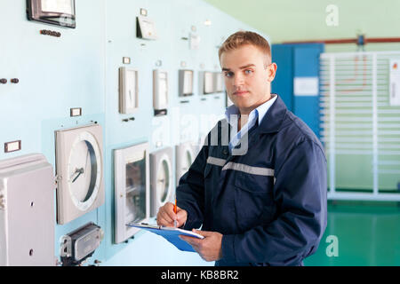 Portrait of young engineer taking notes at control room Stock Photo