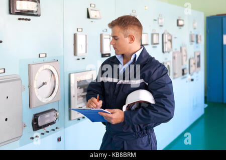 Portrait of young engineer taking notes at control room Stock Photo