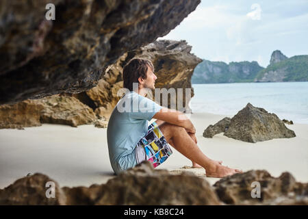 Handsome man sitting on the beach in cave. Relax concept Stock Photo