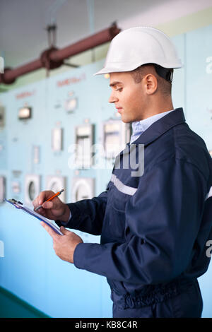 Portrait of young engineer taking notes at control room Stock Photo