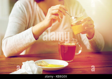 close up of woman adding honey to tea with lemon Stock Photo