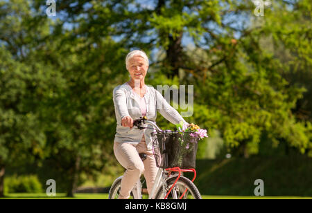 happy senior woman riding bicycle at summer park Stock Photo