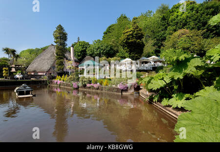 Rose Cottage Tea Gardens, Cockington, Torquay Devon UK - View across the lawn and stream with, tea terraces, thatched cot and bandstand in background Stock Photo