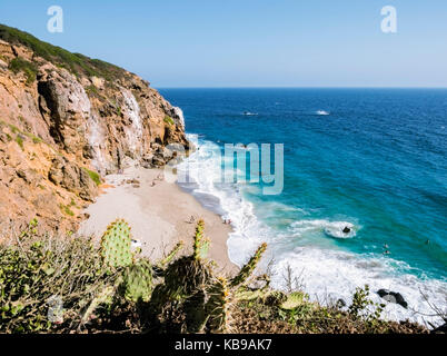 Dume Cove Malibu Beach, view from Dume Point overlook at Zuma Beach, emerald and blue water in a quite paradise beach surrounded by cliffs and cactus  Stock Photo
