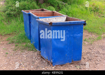 Three empty garbage cans on the green grass Stock Photo