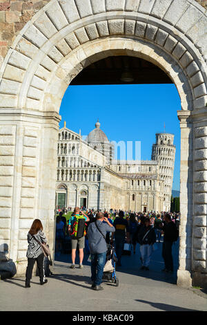 Tourists walk into the Piazza dei Miracoli with the Leaning Tower of Pisa in the background, Pisa, Itali Stock Photo