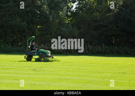 orker Cutting grass on field with lawnmower Stock Photo