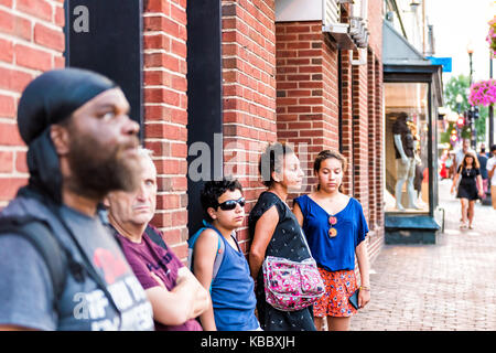 Washington DC, USA - August 4, 2017: People walking on sidewalk waiting in line queue for bus at Georgetown evening downtown neighborhood Stock Photo