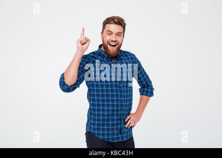 Happy cheerful bearded man pointing finger up and having an idea while standing isolated over white background Stock Photo