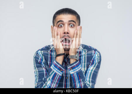 Human face expressions and emotions. Man holding arms on her cheeks, opened mouth and scream. Isolated studio shot on gray background. Stock Photo