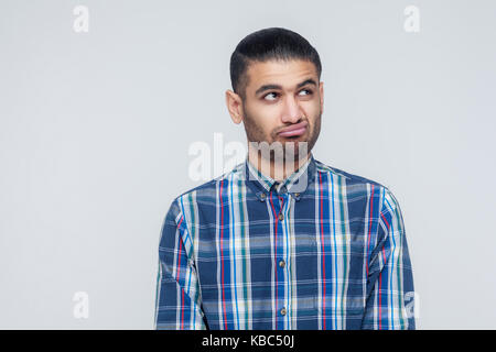 Thoughtful bearded businessman looking away while standing against gray wall. Studio shot Stock Photo