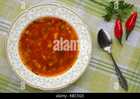 Homemade delicious traditional bulgarian bean soup (bob chorba) with pepper, tomatoes, onion and spices, served with red chili peppers Stock Photo