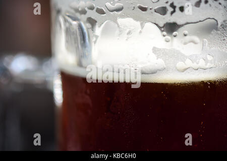 Close-Up Of Refreshing Cold Pint Of Dark Ale Beer With Condensation, Frothy Foam And Bubbles Ready To Drink Stock Photo