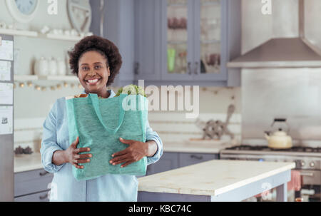 Smiling African woman standing at home with a shopping bag Stock Photo