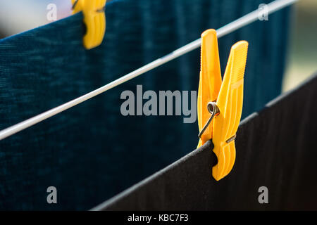 Extreme Close-Up Of Yellow Plastic Clothespin Holding Black T-Shirt On Wire Stock Photo