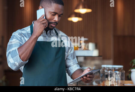 Young African entrepreneur hard at work in his cafe  Stock Photo