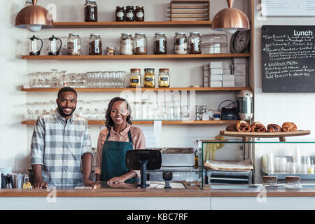 Two smiling young African entrepreneurs standing at their bakery counter Stock Photo