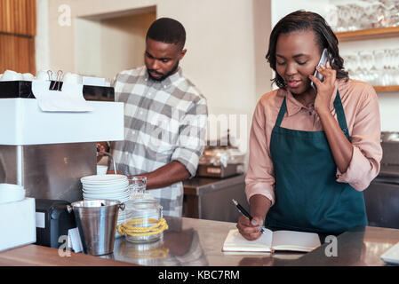 Two young African entrepreneurs hard at work in their cafe Stock Photo