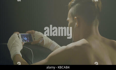 Boxer looks in the phone. Rear view of a boxer who looks match his rival on the phone Stock Photo