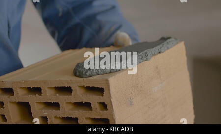 Construction of brick wall. Trowel spreading cement on bricks. Worker spreads cement for bricks Stock Photo