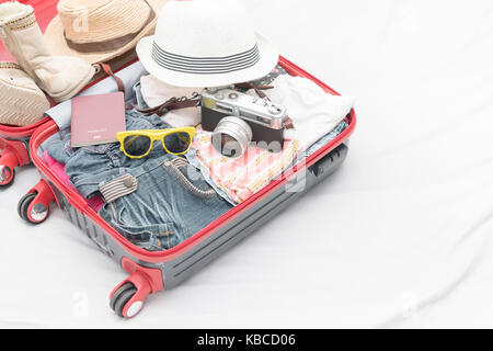 Travel accessories costumes. Passport, luggage, camera, sunglasses, boot, clothes in suitcase on bed, prepared for the trip and travel concept Stock Photo