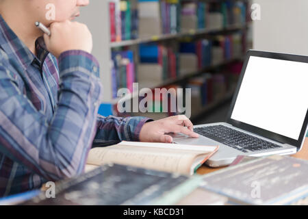 young student preparing exam and learning lessons in school library, making research on laptop and browse internet, education concept Stock Photo
