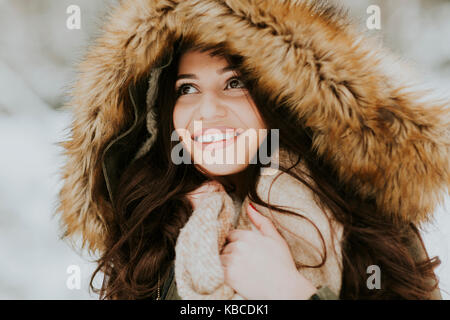 Pretty young woman with hood in the park on the winter day Stock Photo