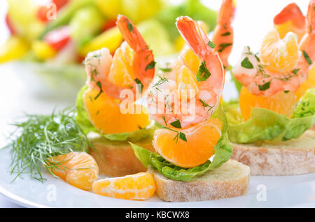 Scampi skewers with mandarin on Italian bread Stock Photo