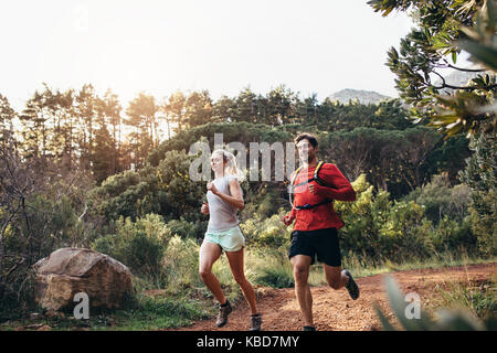 Man and woman jogging on a muddy park trail. Morning jogging couple running together. Stock Photo
