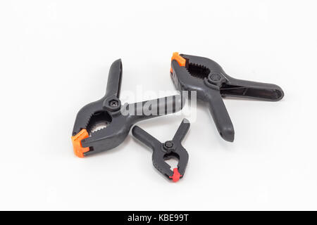 Three spring clamps, two big and one small, for a photographic studio, on a white surface. Stock Photo