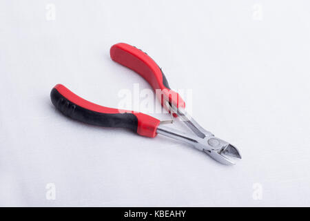 A wire cutter with a black and red handle on a white surface Stock Photo