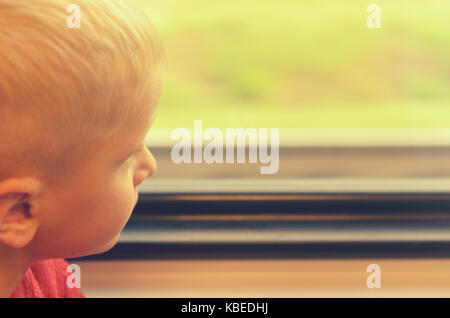 The boy looks out the window of the train car Stock Photo