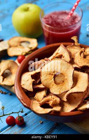closeup of some slices of dried apple served as appetizer or snack, on a blue rustic wooden table Stock Photo