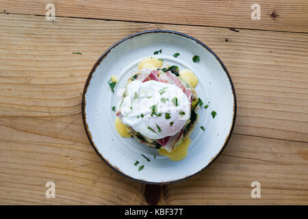 rustic tasty eggs benedict on plate on wooden table Stock Photo