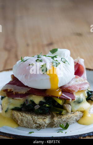 rustic tasty eggs benedict on plate on wooden table Stock Photo